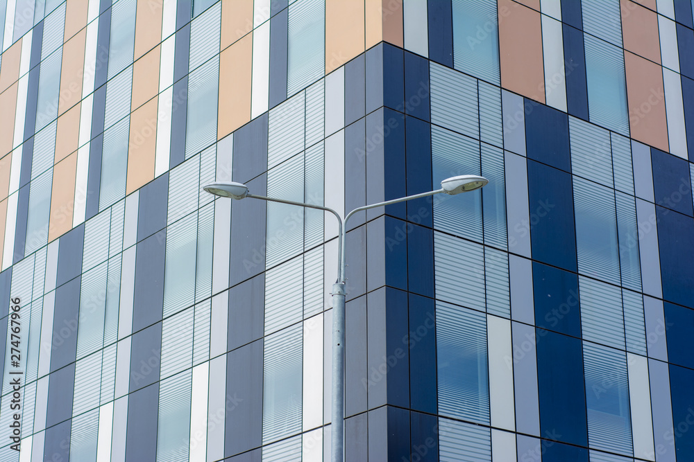A pillar with street lamps against the backdrop of a modern building. Concept - view of the sleeping area of a big city with cozy courtyards. A pillar with street lamps against the backdrop of a modern building. Concept - view of the sleeping area of a big city with cozy courtyards.