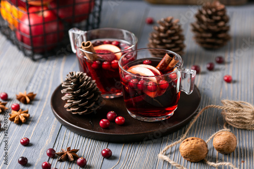 Mulled wine in glasses on a wooden background. Apples, cranberries, cinnamon, star anise.