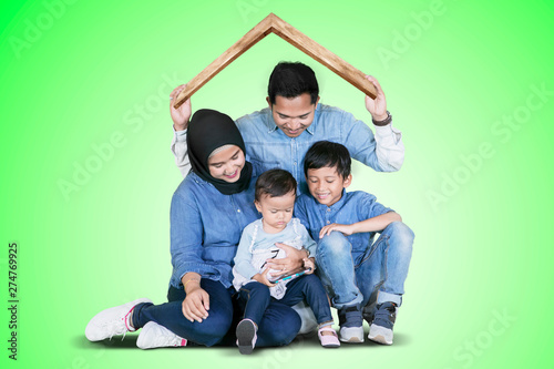 Muslim family plays under a roof symbol on studio © Creativa Images
