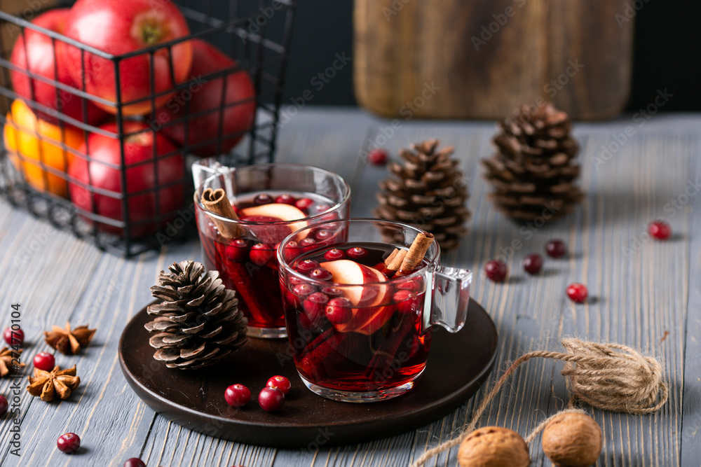 Mulled wine in glasses on a wooden background. Apples, cranberries, cinnamon, star anise.