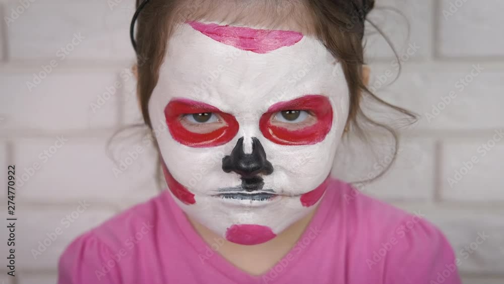 Angry child for Halloween. Little girl with painted face for halloween.