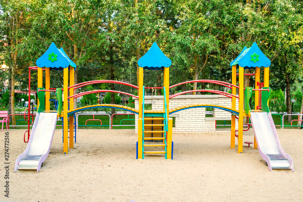 Colorful children playground activities in public park surrounded by green trees