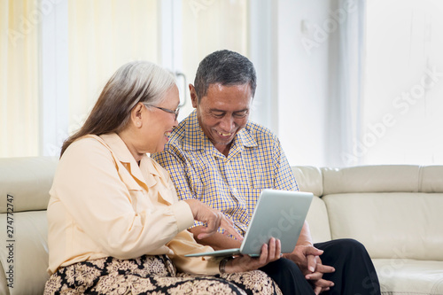 Senior couple looks happy with laptop at home