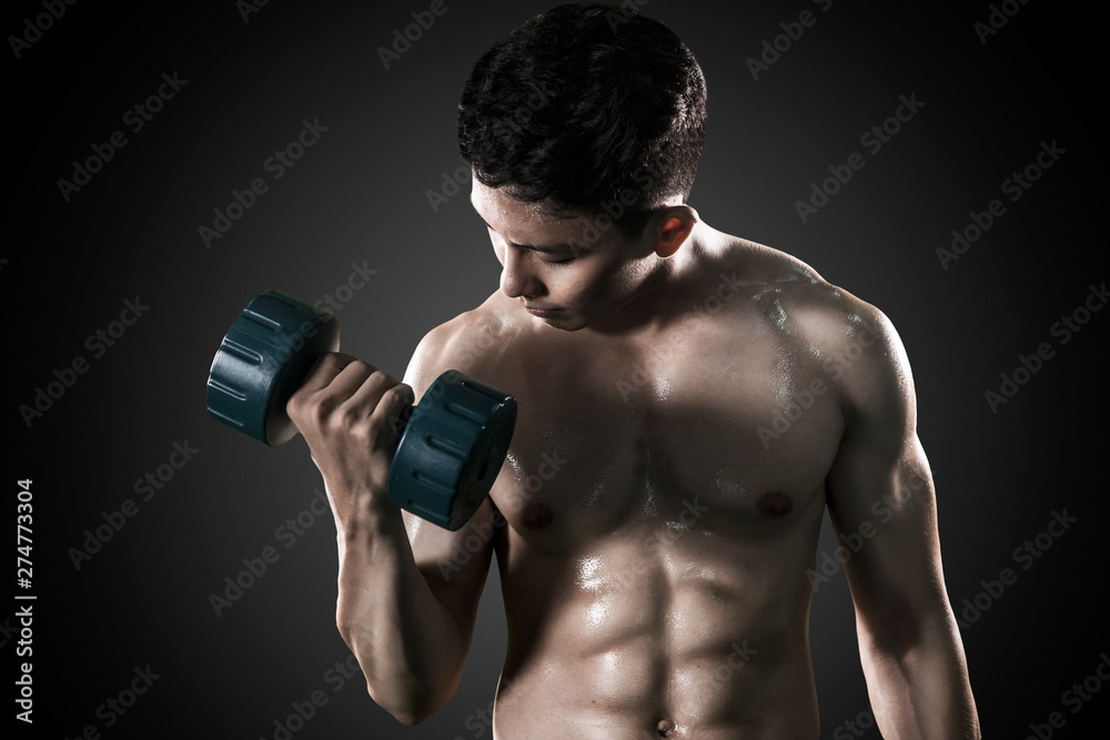 Shirtless young man exercising his muscular biceps