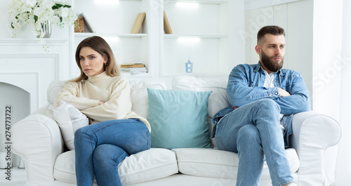 Relationship Problems. Couple Sitting On Different Sides Of Couch
