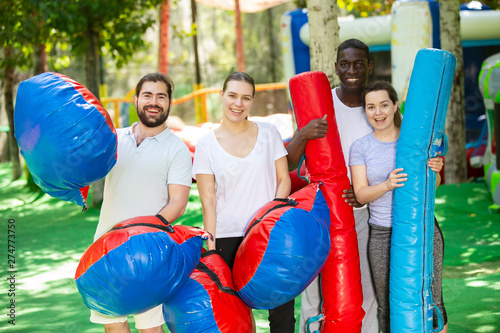 Portrait of happy friends with inflatable logs and pillows at an amusement park photo