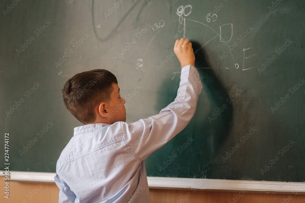 Little boy white down something on blackboard. Clever male Little boy white down something on blackboard. Clever male