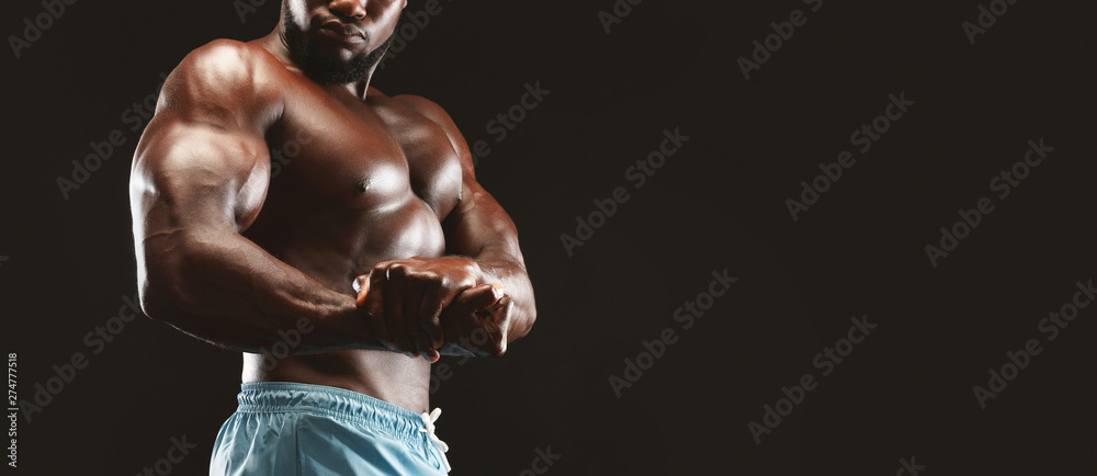Fototapeta premium Muscular african man demonstrating strong hands, flexing biceps