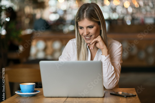 Beautiful businesswoman  typing an e-mail on laptop in a cafe