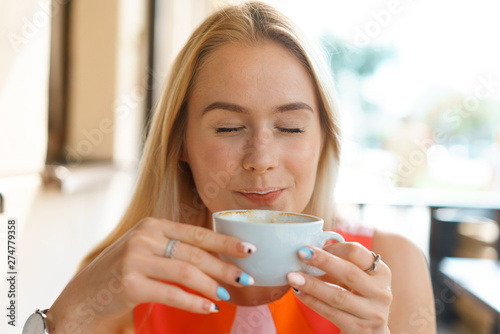 young beautiful blond woman sit at table in cafe drink coffee wait for businesspartner have a business meeting