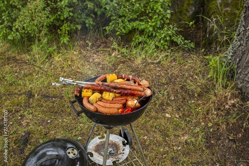 Close up view of iron grill with sausages and corn. Outdoor food cooking concept.