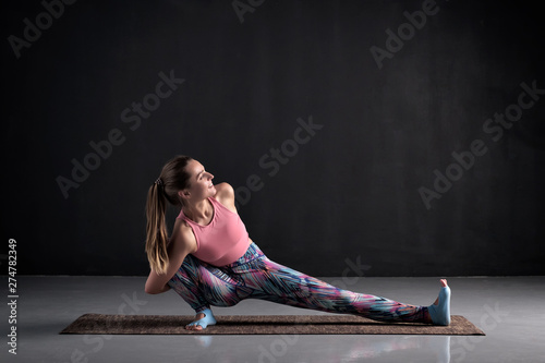 Beautiful young woman doing Skandasana yoga pose photo