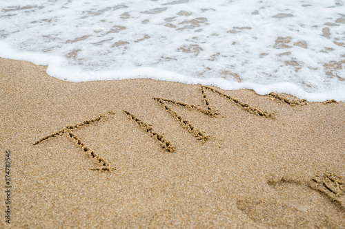 Time is the ultimate concept. The word Time written in the sand and disappearing under the influence of the sea wave.