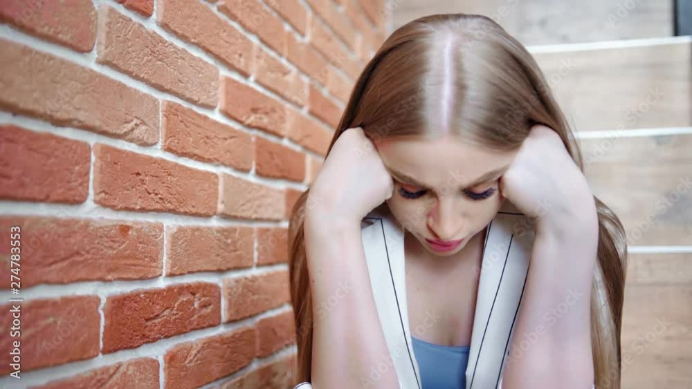 Worried upset young woman holding head by hand having hurt and loss feeling medium close-up Worried upset young woman holding head by hand having hurt and loss feeling medium close-up