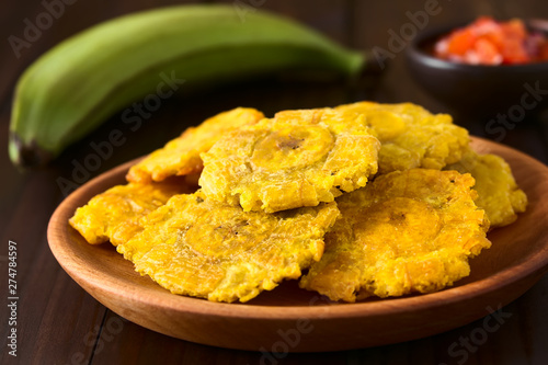 Patacon or toston fried and flattened pieces of green plantains, a traditional snack or accompaniment in the Caribbean (Selective Focus on the front of the top patacon) photo