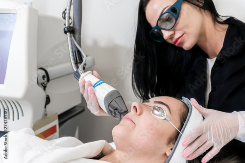 Beauty laser technician performing skin resurfacing procedure in a medical spa and beauty clinic. Caucasian female patient.