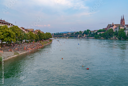 Bild auf Leinwand Outdoor sunny scenery of promenade and bridge along riverside, Basel's cityscape, Münster Cathedral and people float and swim, from Middle Bridge cross Rhine river in Basel, Switzerland in summer