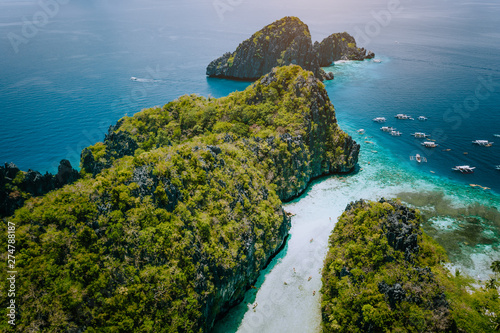Aerial drone view of entrance to shallow tropical Big and Small Lagoon explored inside by tourist on kayaks surrounded by jagged limestone karst cliffs. El Nido, Palawan Philippines © Igor Tichonow