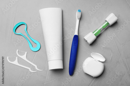 Flat lay composition with tongue cleaner and teeth care products on grey background