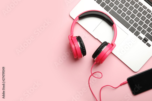 Modern headphones, phone and laptop on color background, flat lay. Space for text