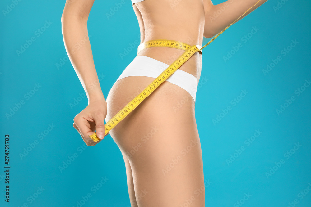 Slim young woman with smooth gentle skin in underwear measuring body on color background, closeup Slim young woman with smooth gentle skin in underwear measuring body on color background, closeup