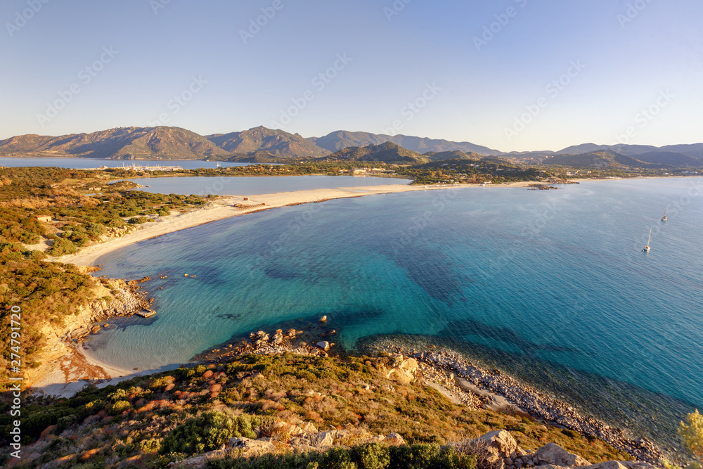 Aerial panoramic view of the beach and sea with azure turquoise crystal clear water, mountains in the background, in Villasimius, Sardinia (Sardegna) island, Italy. Holidays, best beaches in Sardinia.