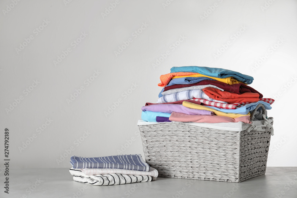 Wicker laundry basket with clean clothes on table against light background.  Space for text Stock Photo | Adobe Stock