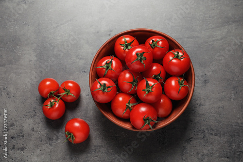 Bowl with ripe cherry tomatoes on color background, top view