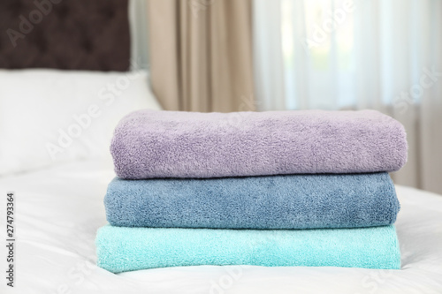 Stack of folded clean soft towels on bed
