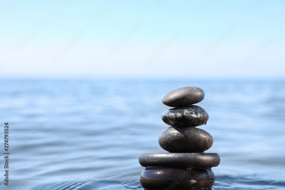 Fototapeta premium Stack of stones in sea water, space for text. Zen concept
