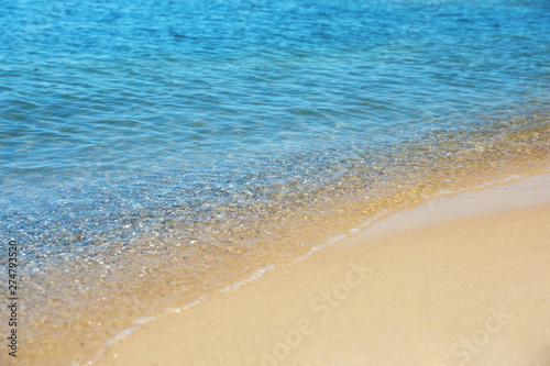 View of sea water and beach sand on sunny day