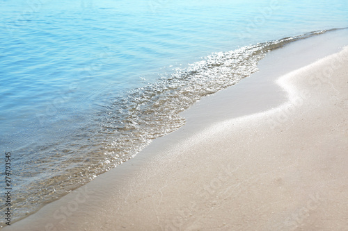 View of sea water and beach sand on sunny summer day