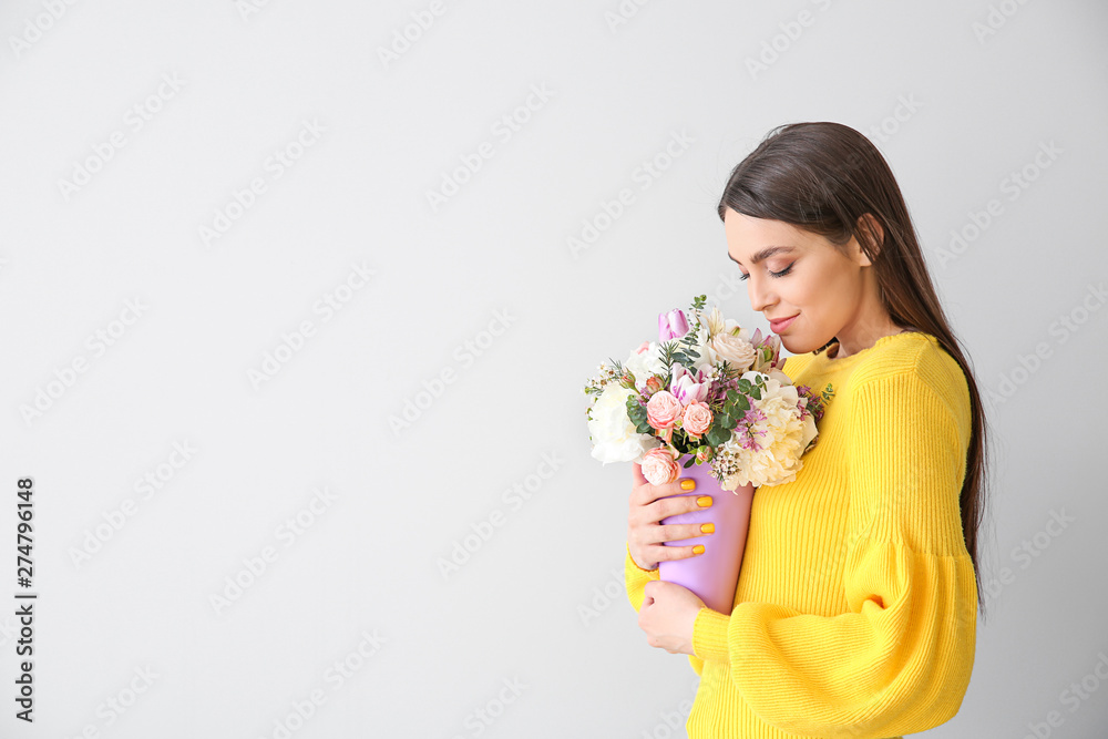 Beautiful young woman with bouquet of flowers on light background Beautiful young woman with bouquet of flowers on light background