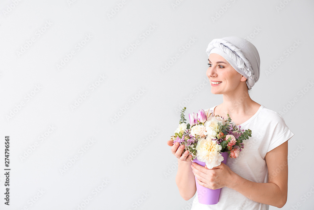 Woman after chemotherapy with bouquet of flowers on light background Woman after chemotherapy with bouquet of flowers on light background
