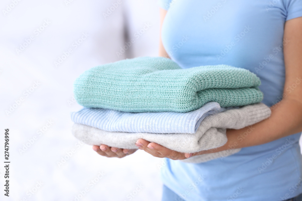 Young woman with stack of clean clothes at home, closeup Young woman with stack of clean clothes at home, closeup
