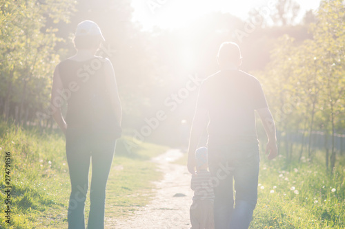 Back of Caucasian Family of Three Together Outdoors Having a Stroll.