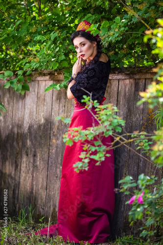 Glamour Fashion Model in Russian Style Decorated Kokoshnik Posing Outdoors Against Old Wooden Fence.