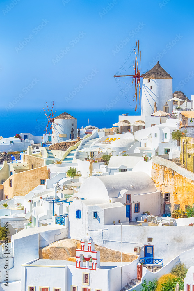 Fototapeta premium Travel Destinations. Picturesque Cityscape of Oia Village in Santorini Island Located on Volcanic Calderra at Daytime. Traditional Windmills on Background.
