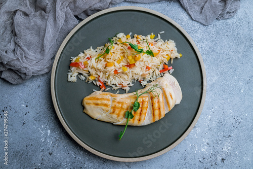 sliced Grilled chicken Breasts with rice and vegetables on grey plate