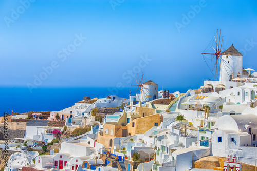 Travel Destinations. Picturesque Cityscape of Oia Village in Santorini Island Located on Volcanic Calderra at Daytime. Traditional Windmills on Background.