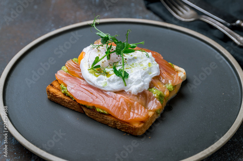 poached egg with salmon and avocado on a white plate