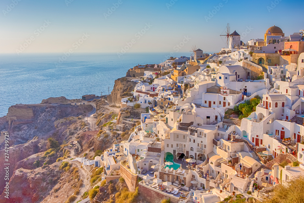 Picturesque Cityscape of Oia Village in Santorini Island Located on Red Volcanic Calderra at Daytime with Windmills on Background.