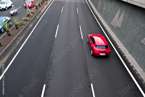 A red car in movement on a black asplalt road, intentional movement / zoom effect. © Daguimagery