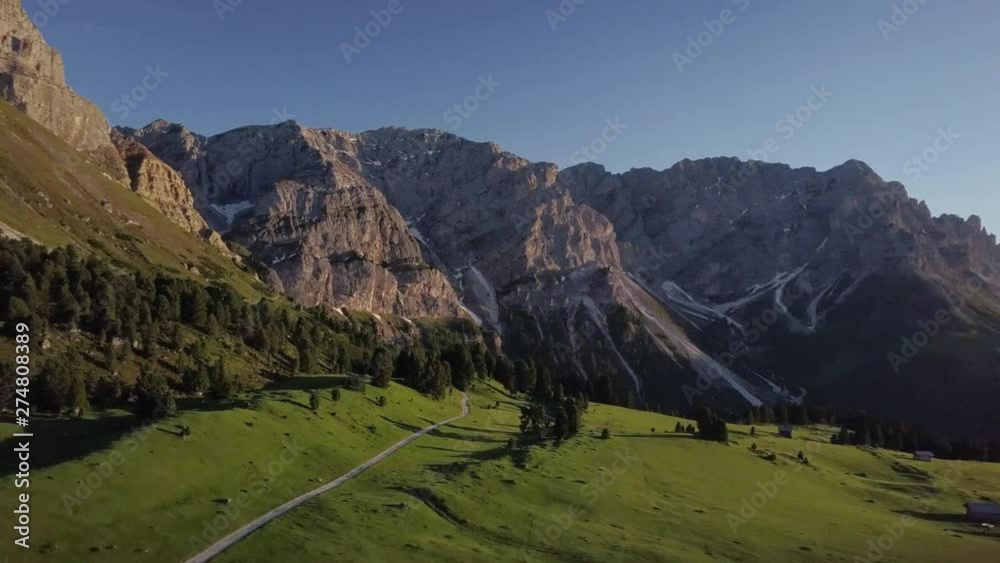 Aerial panning shot of the slopes of the mountains of Dolomites in northeastern Italy in the sun Aerial panning shot of the slopes of the mountains of Dolomites in northeastern Italy in the sun