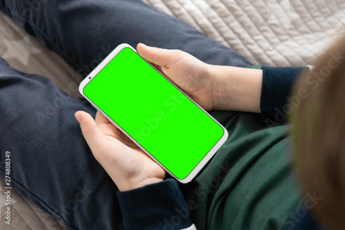 Smartphone with a hromakey in the hands of a child. Smartphone with a green screen in hand child . Phone a for keying is holding kid. photo