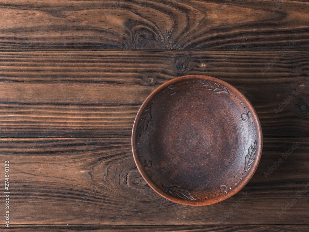 Clay bowl on a brown wooden table. Flat lay.