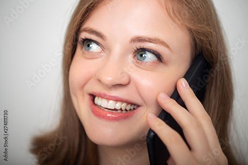 Young caucasian girl woman is talking on the mobile phone and smiling, close up