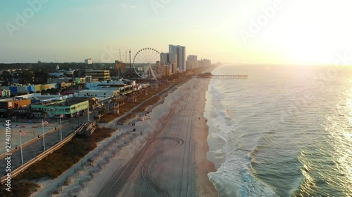 Aerial Push-in Over Myrtle Beach Coastline Toward Skywheel and Pier during Golden Hour photo
