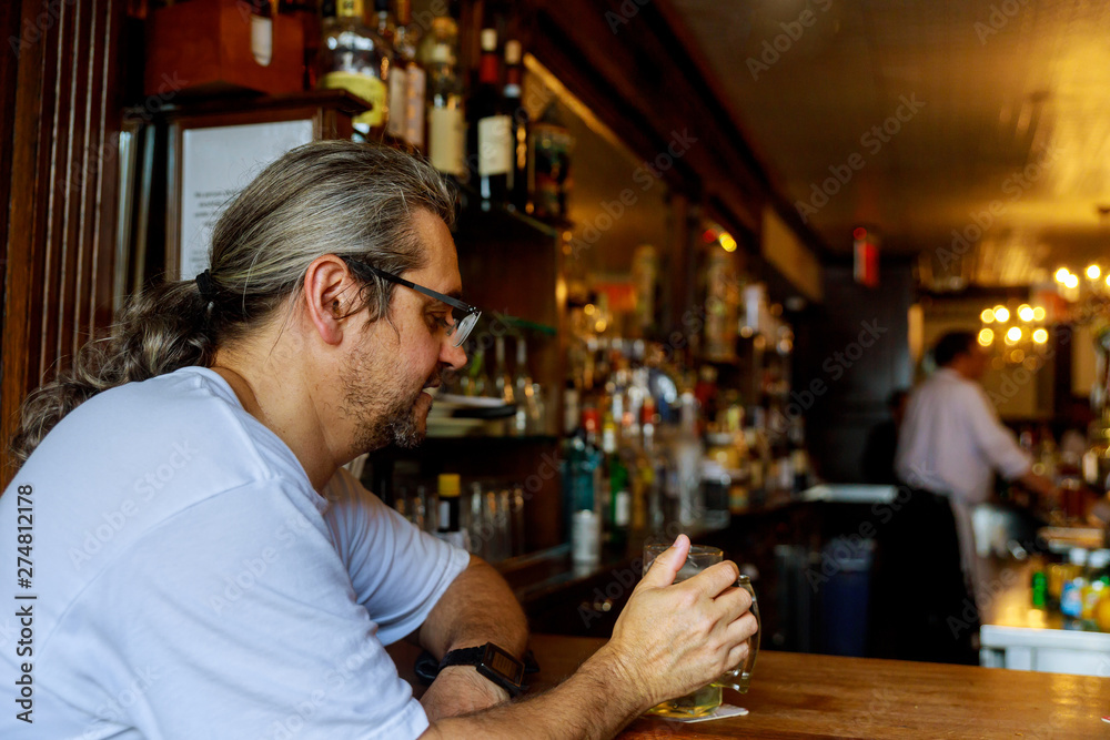Cheerful american young man drinking beer in pub
