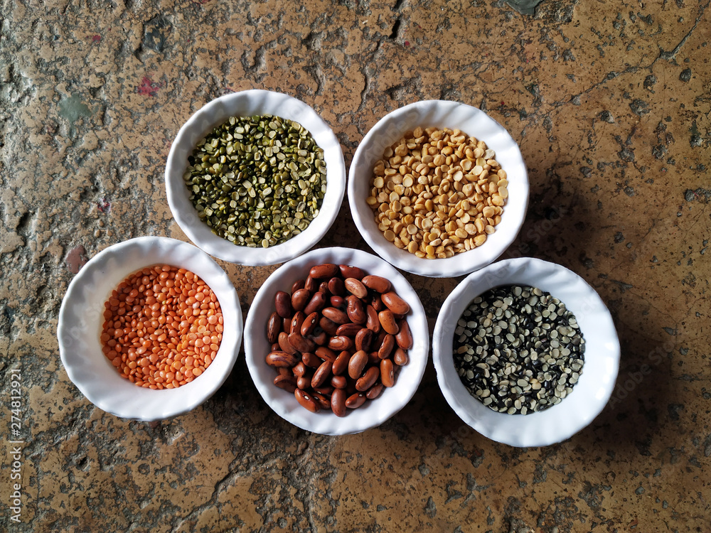 Uncooked pulses,grains and seeds in White bowls over stone background. selective focus Uncooked pulses,grains and seeds in White bowls over stone background. selective focus